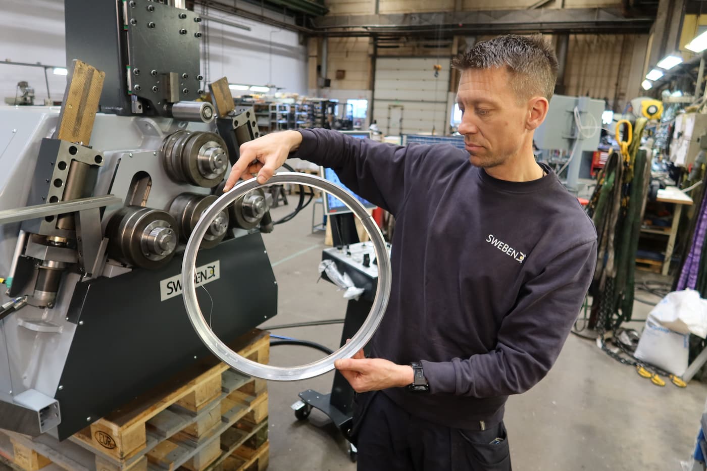 SweBend engineer holding the finished aluminium shroud ring produced using a customized section bending solution. SweBend engineer holding the finished aluminium shroud ring produced using a customized section bending solution.