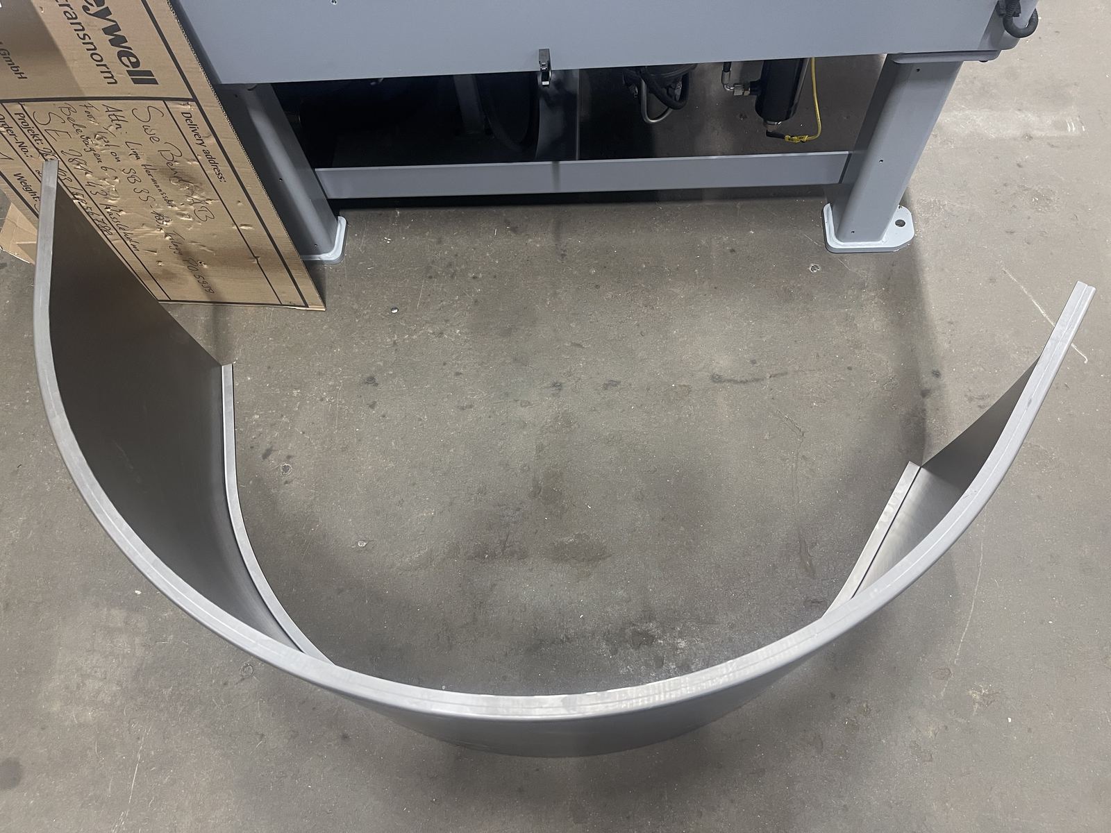 Finished bent flanged plate on the factory floor showing consistent curve produced by the SweBend SB3-105 CNC