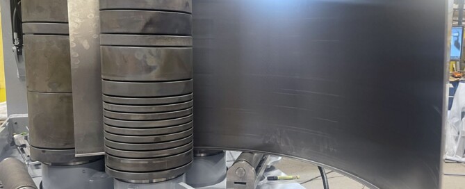 SweBend SB3-105 CNC section bending machine with flanged plate loaded between profiled rolls and hydraulic guide rolls