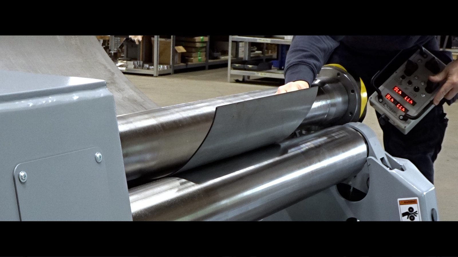 Operator using wireless Bluetooth control unit while standing beside the SweBend PB3-6-4 plate bending machine during cone forming